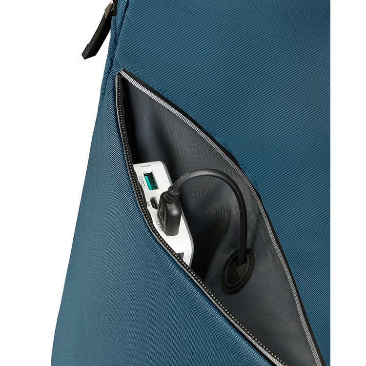 Primer plano de un bolsillo de mochila verde azulado. Dentro hay un banco de energía blanco con un cable negro.