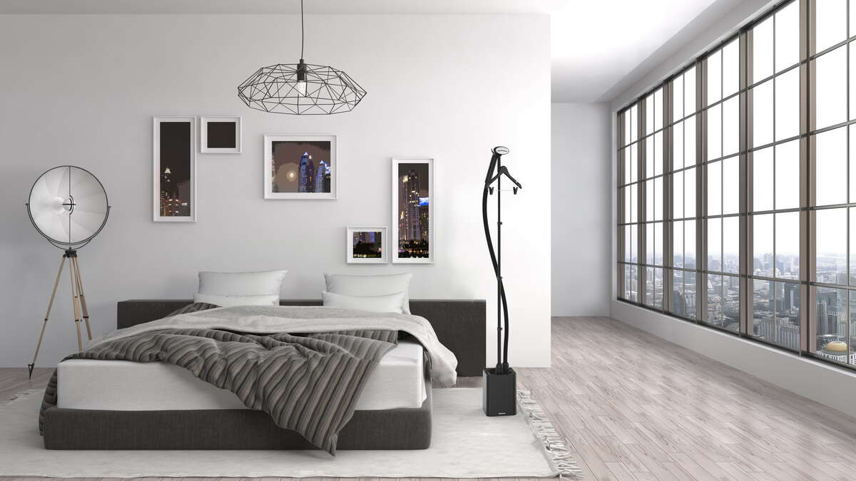 Chambre avec lit, tableaux, lampe et défroisseur.