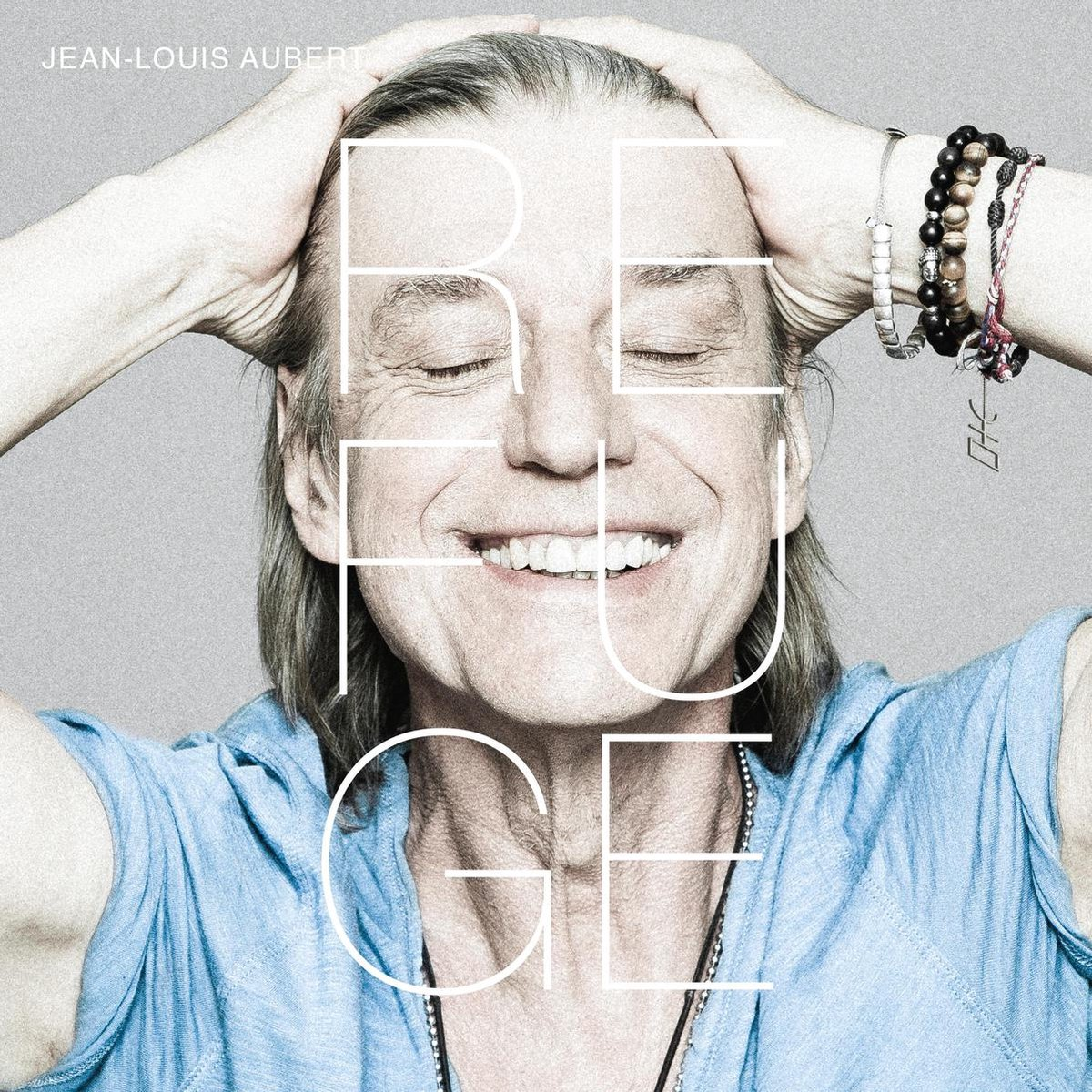 Albumhoes van Jean-Louis Aubert. Man lacht, handen op hoofd, woord 'REFUGE'.