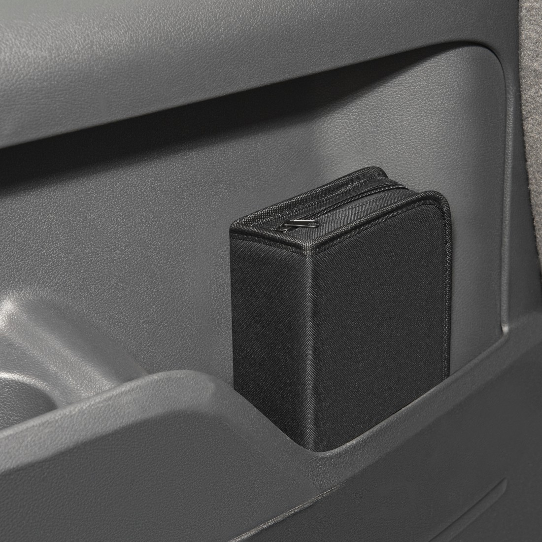Schwarzes Etui im Türfach eines Autos. Mit Reißverschluss. Grauer Innenraum.