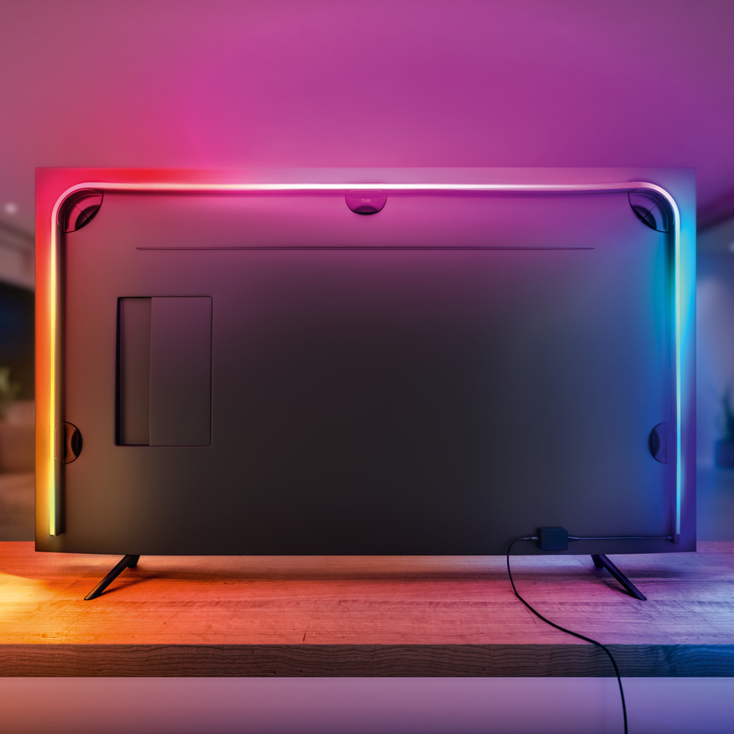 TV back with colorful LED lights, on a wooden table, wires connected.