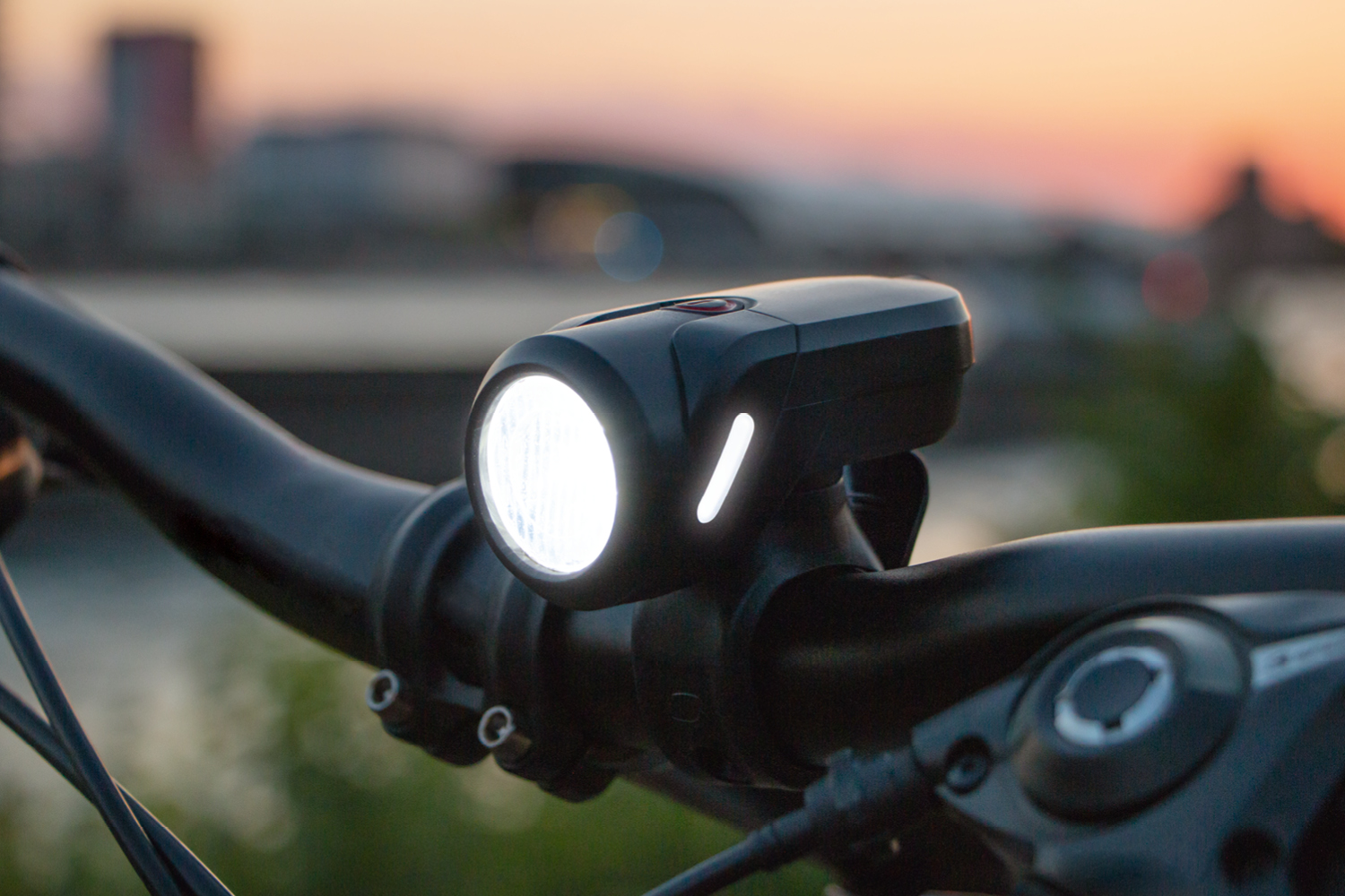 Fahrradscheinwerfer am Lenker montiert. Sonnenuntergang im Hintergrund.