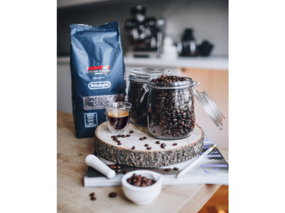 Granos de café, espresso y accesorios dispuestos sobre una superficie de madera con un periódico.