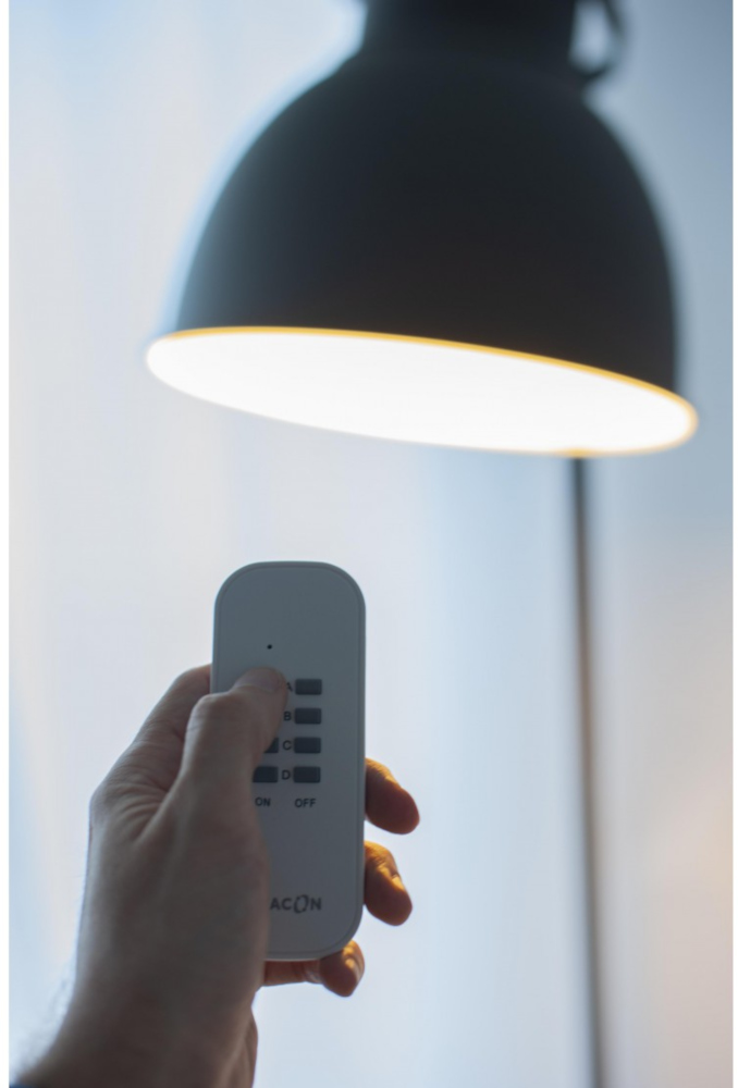 Hand die een afstandsbediening vasthoudt en naar een zwarte lamp wijst.