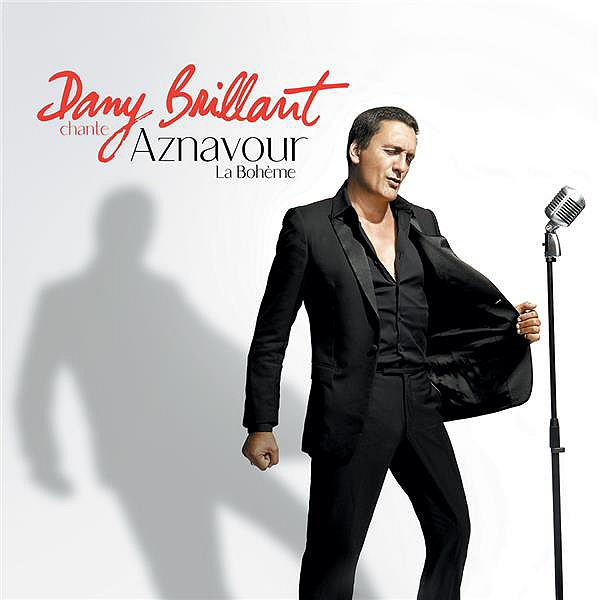 Pochette d'album Dany Brillant. Chanteur en costume noir, ombre sur le mur, microphone.