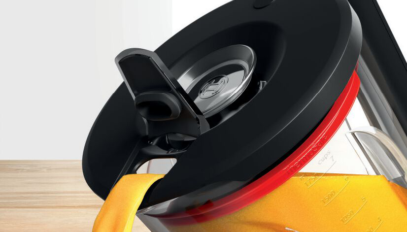 Orange juice pouring from a black and red jug. Close-up view.