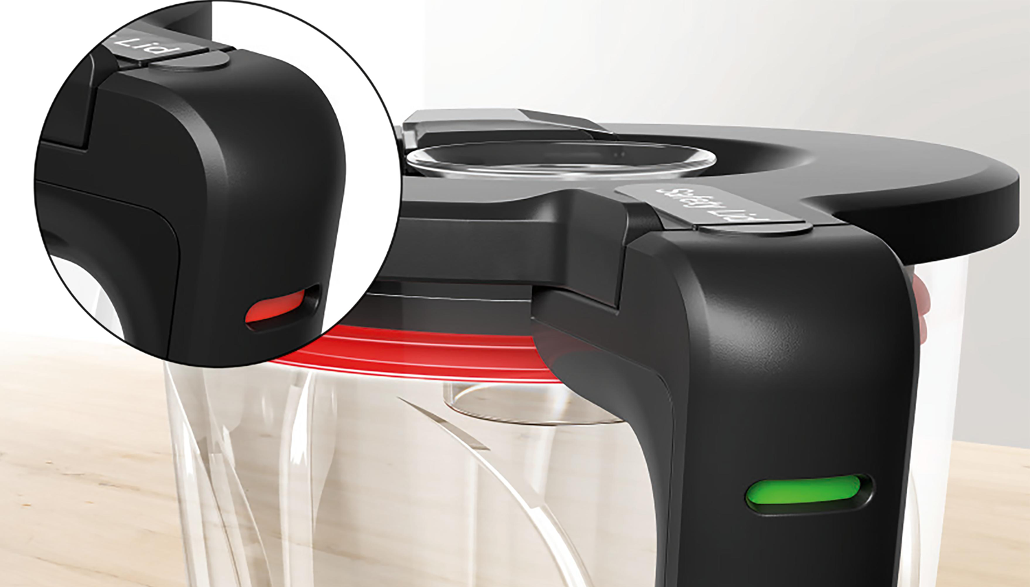 A close-up of a black lid with a red and green light indicator. The lid reads 'Safety Lid'.
