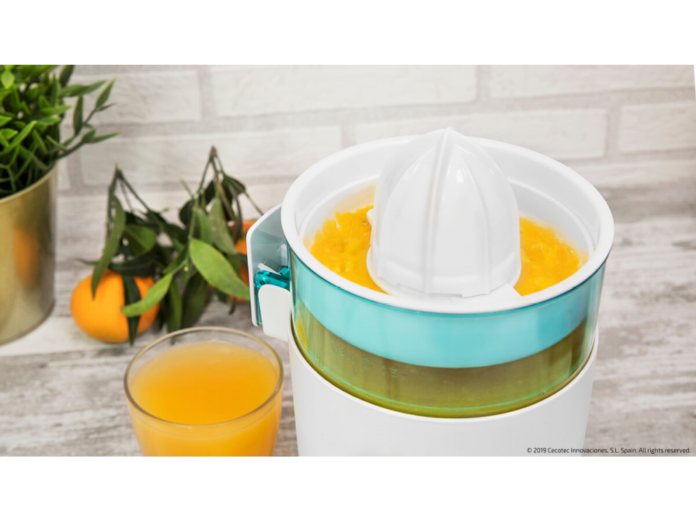 Exprimidor con pulpa de naranja. Jugo de naranja en un vaso, naranjas al fondo.