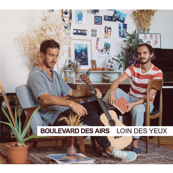 Deux hommes assis avec une guitare et un livre, texte 'Boulevard des Airs'.