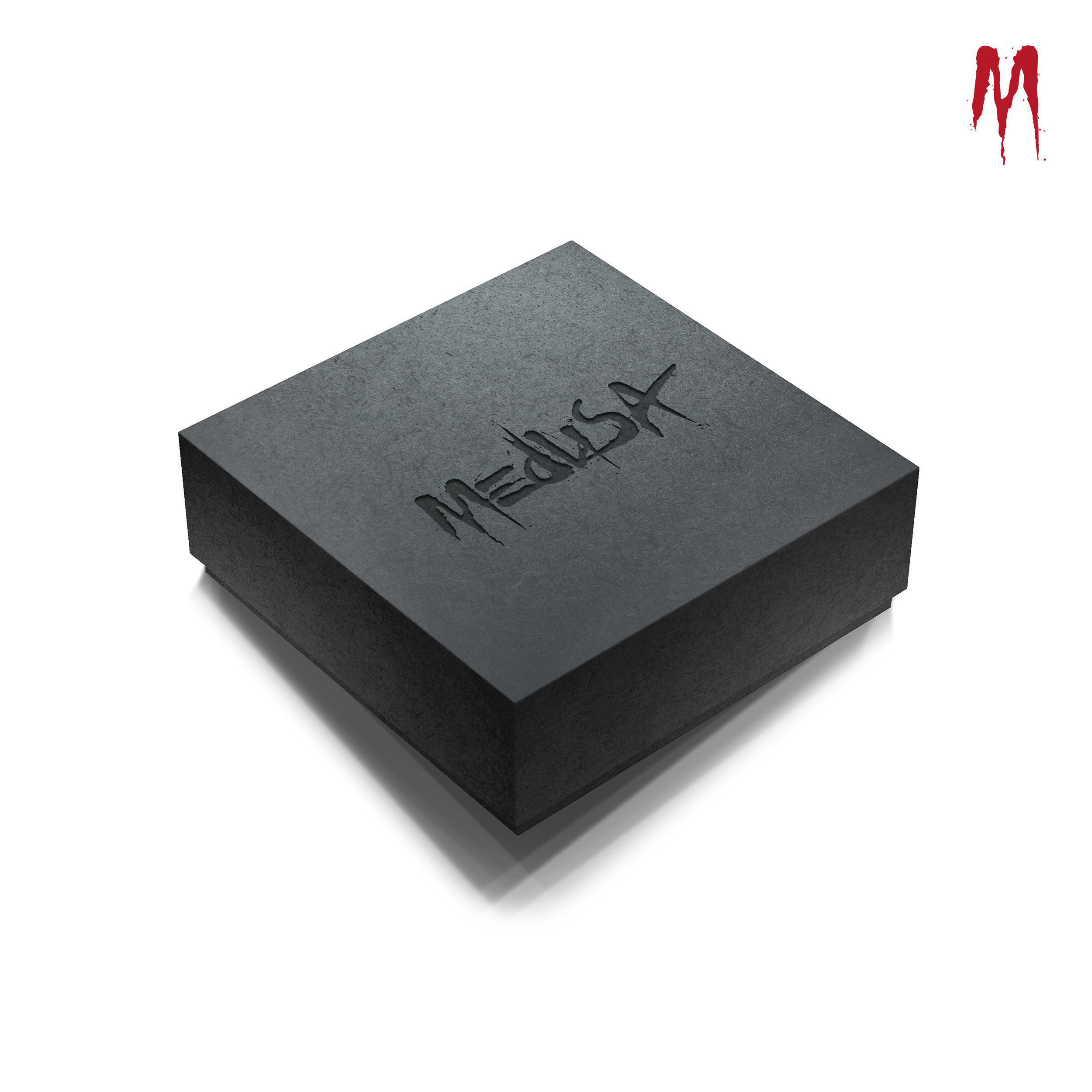 Schwarze quadratische Box mit geprägtem Medusa-Text. Weißer Hintergrund, rotes M-Logo.