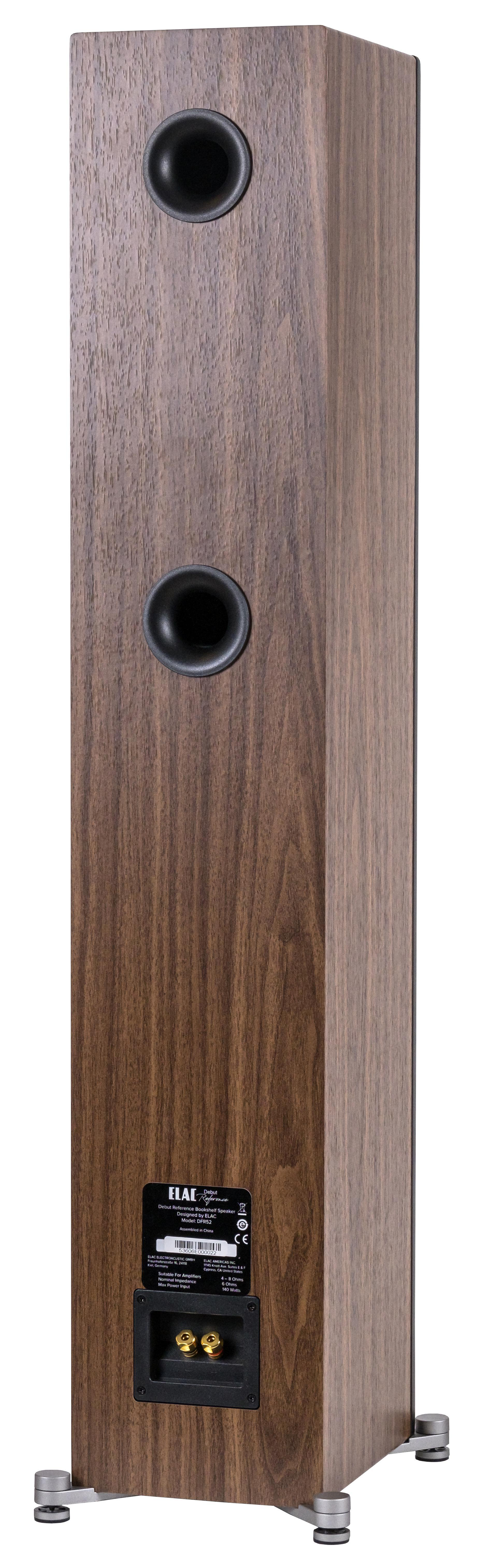Ein hoher Holzspeaker mit zwei schwarzen Anschlüssen, einem Etikett und silbernen Beinen auf weißem Hintergrund.