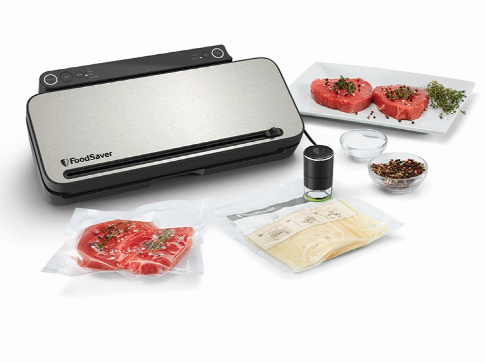 FoodSaver con carne y accesorios. Fondo blanco, vista de cerca.