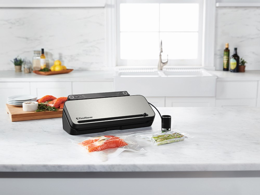 FoodSaver en una encimera de mármol con salmón y espárragos.