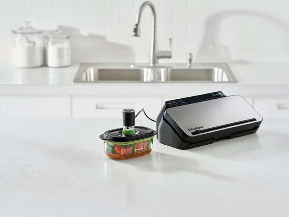 Selladora al vacío con un recipiente de comida y un fregadero en el fondo.
