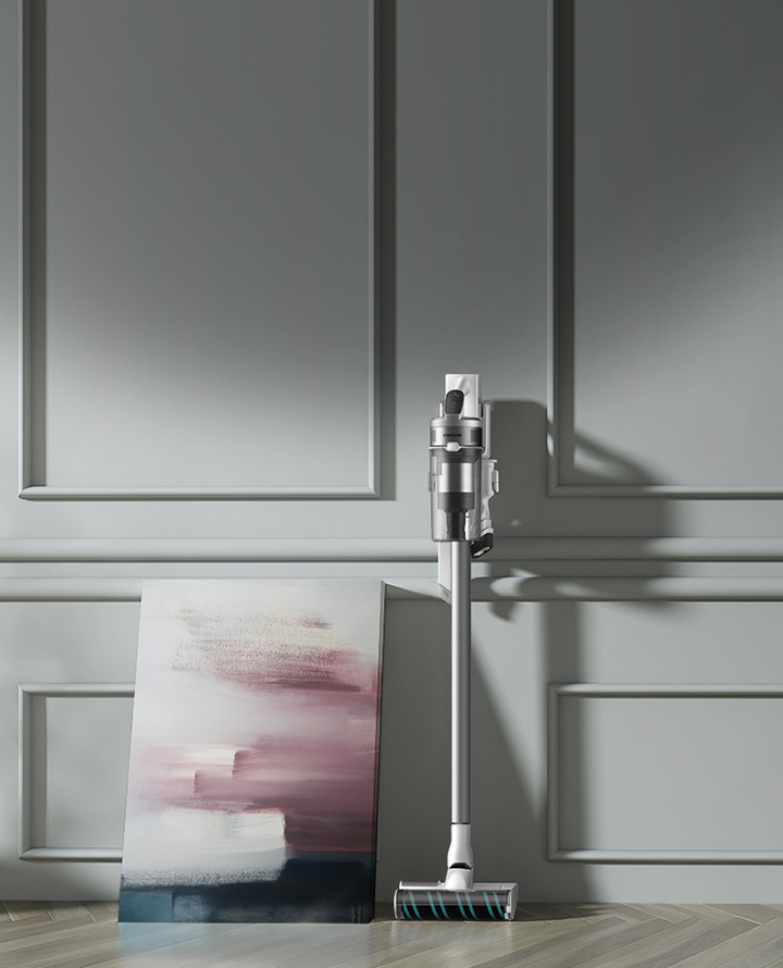 Stofzuiger. Zilverkleur en een schilderij. Grijze muur en witte vloer.