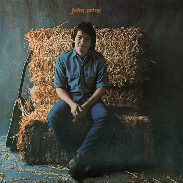 John Prine szénabálákon ül. Farmerben és kék ingben van. Egy gitár balra dől. A háttér egy tompa sötétkék.