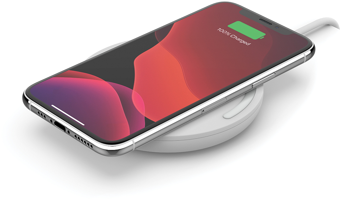 White iPhone on a wireless charger, showing 100% charged on the screen.