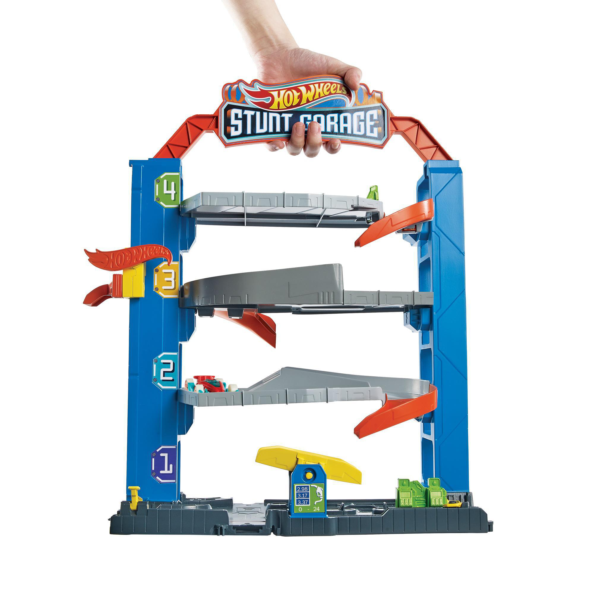 Ein Hot Wheels Stunt Garage Spielset mit Ebenen, Rampen und Spielzeugautos. Eine Hand hält die Oberseite. Blau und rot.