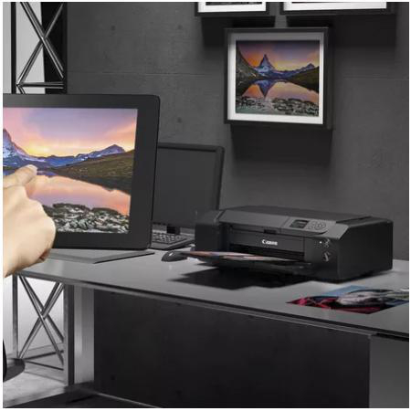 Schreibtisch mit Computer, Drucker und Kunstwerk auf schwarzem Schreibtisch.