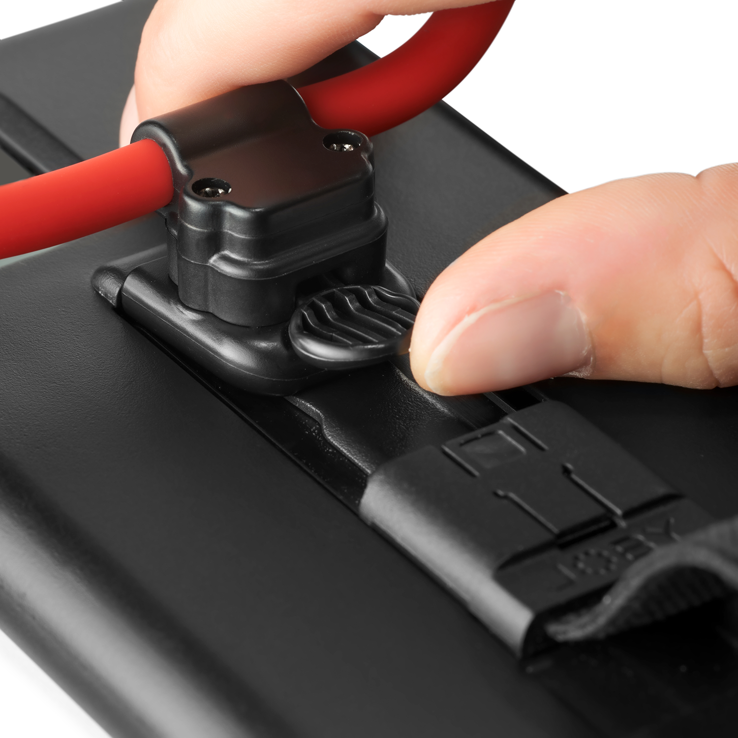 A red band is connected to a black device; a finger presses a button.