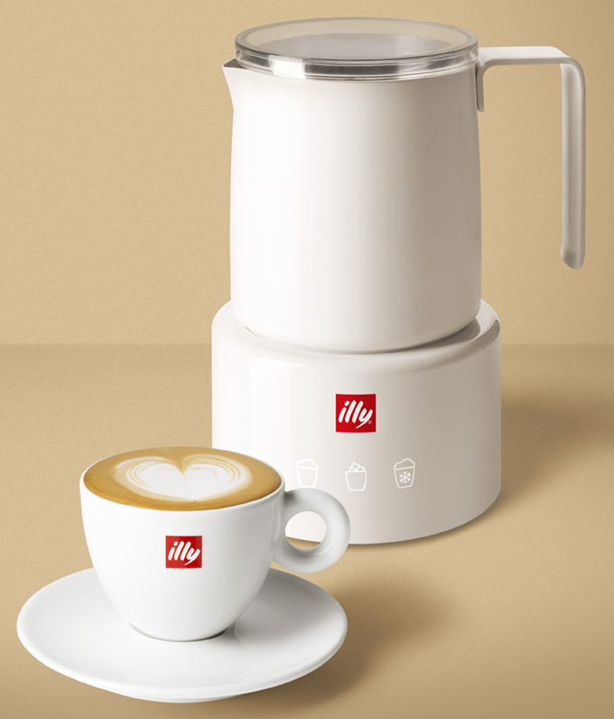 Weißer Kaffeebereiter mit einer Tasse Latte und Untertasse. Der Latte hat ein herzförmiges Design.