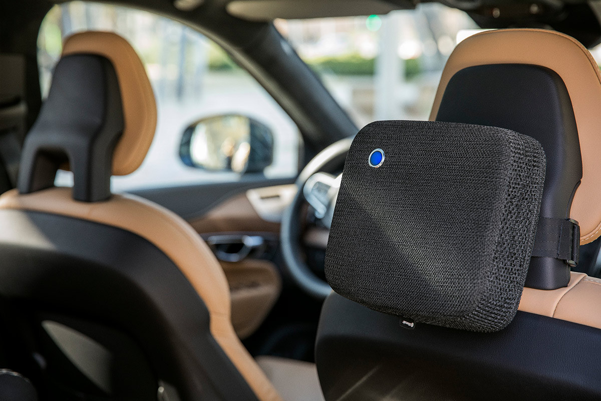 Car interior with a headrest air purifier in the back seat. Beige and brown seats.