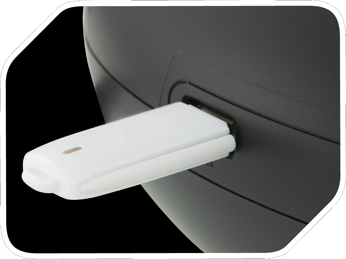 Une clé USB blanche insérée dans un appareil noir, sur fond noir.