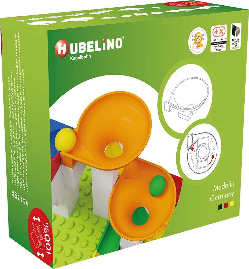 Boîte de blocs de construction pour enfants. Composants en plastique orange et jaune. Fond vert et blanc.