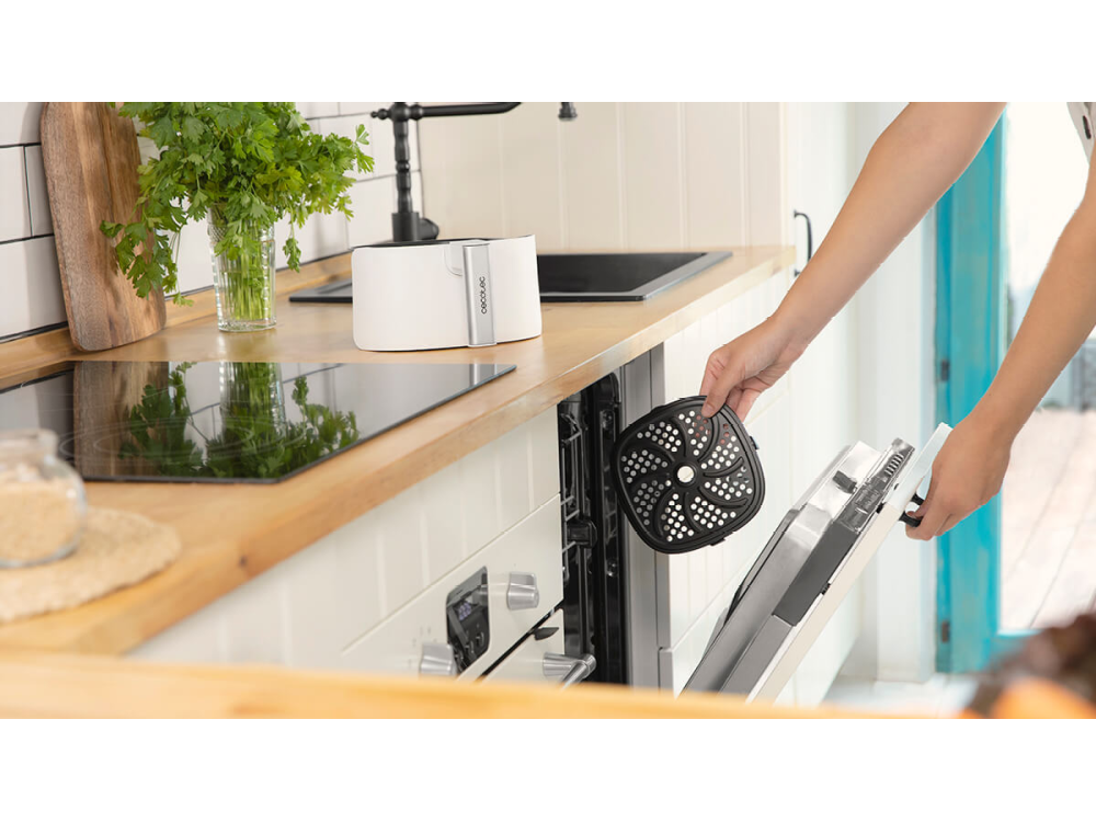 Persona abriendo una freidora de aire, sosteniendo una cesta en una cocina.