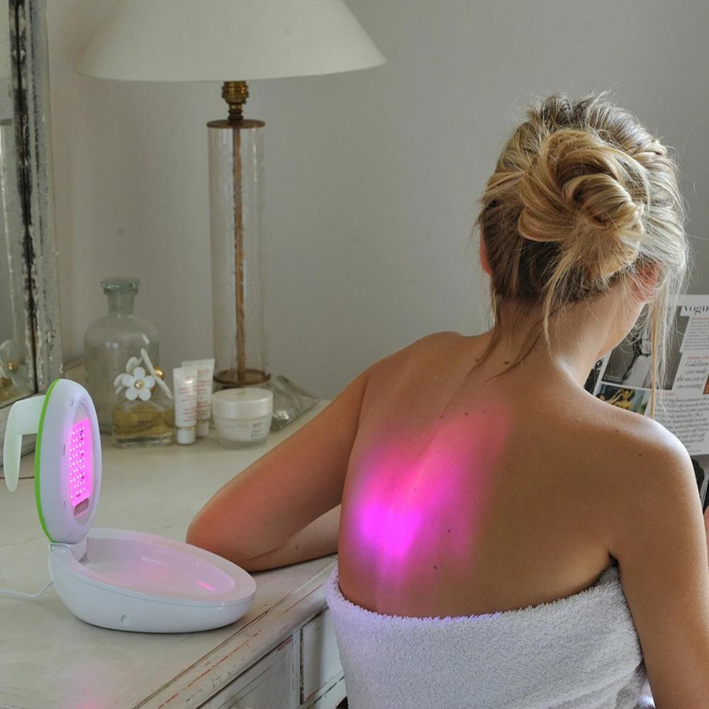 Femme dos nu, recevant une luminothérapie rouge d'un appareil.