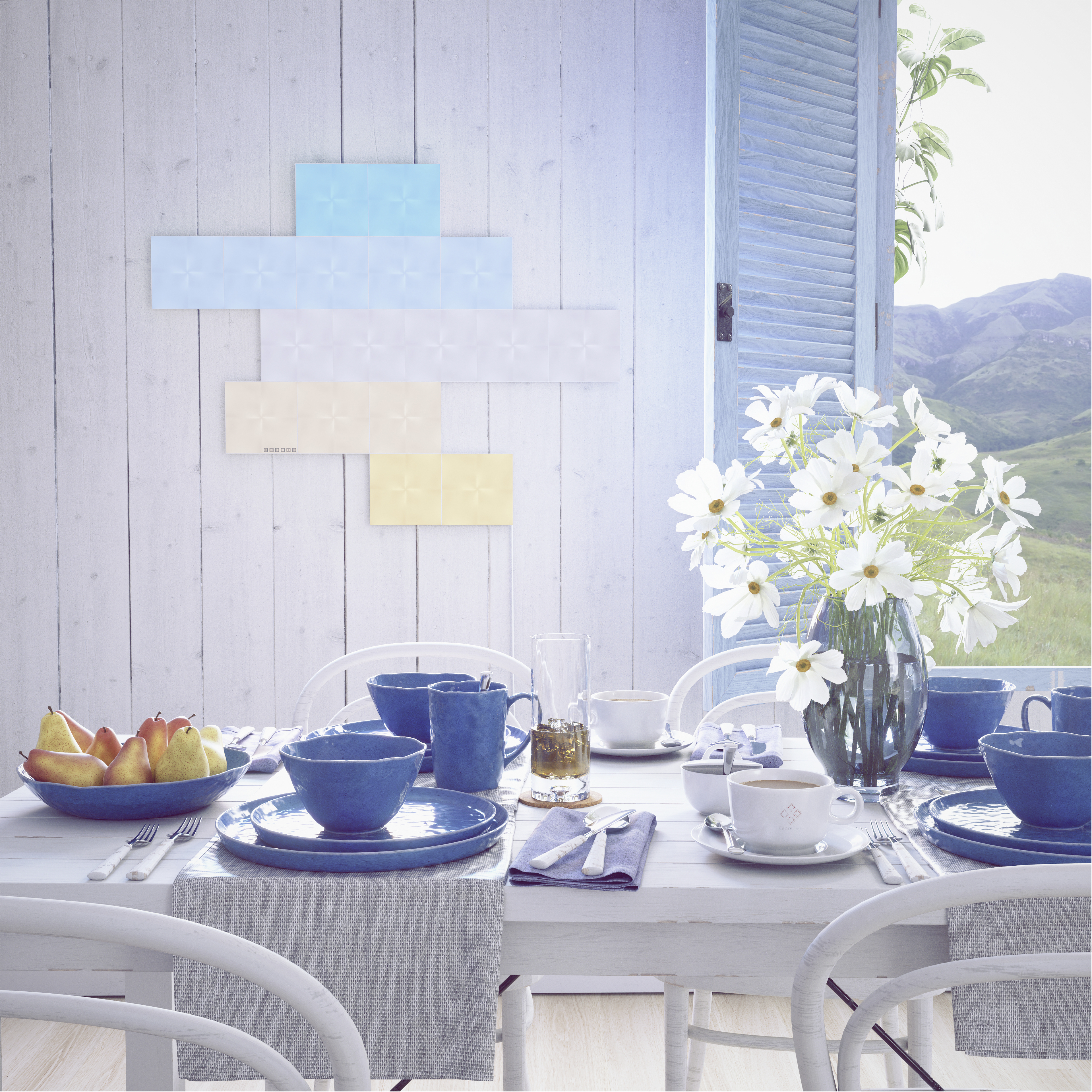 Ein Tisch für eine Mahlzeit mit blauen Gerichten, weißen Blumen und Blick auf Berge durch ein Fenster.