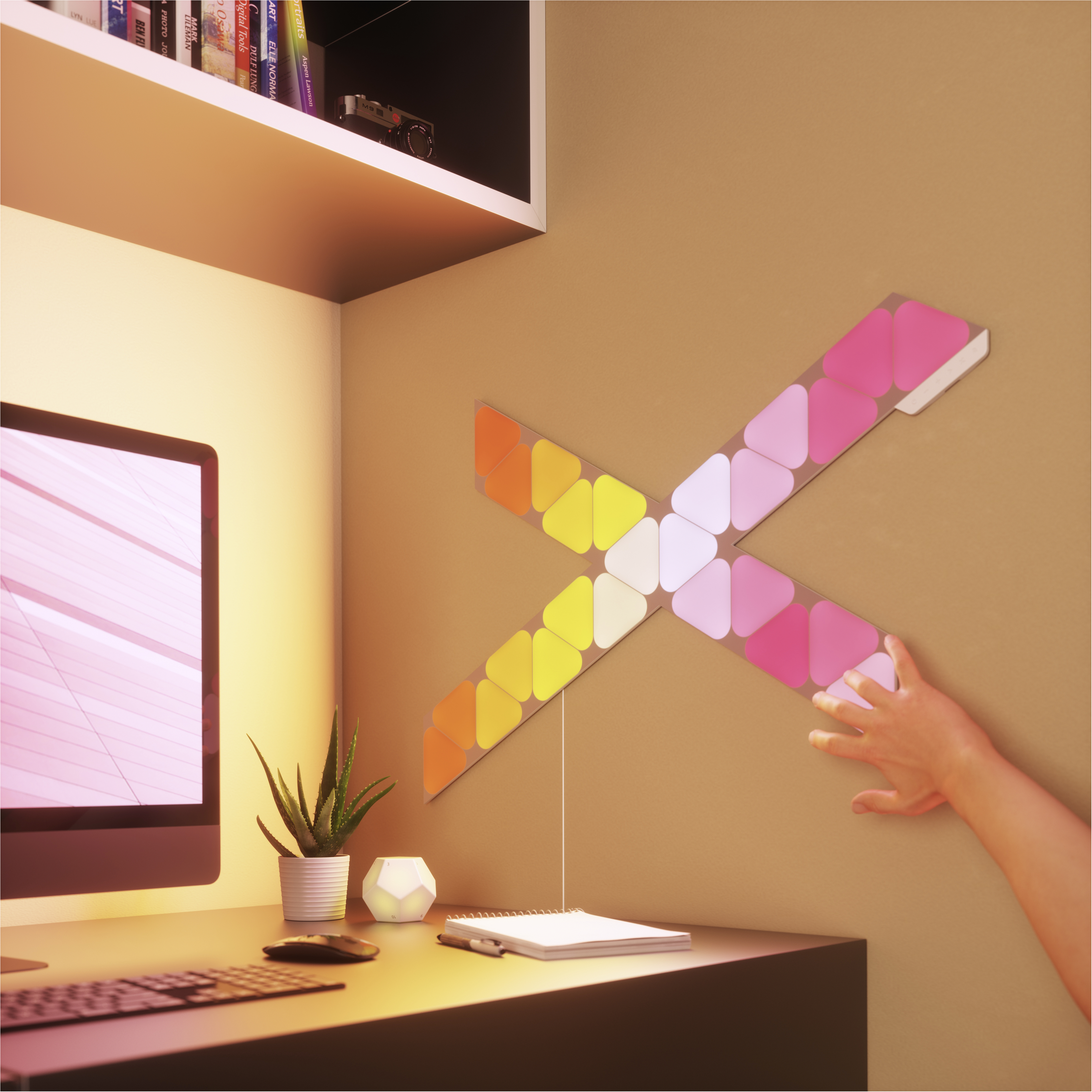 Farbenfrohe Wandkunst in 'X'-Form, mit einer Hand, die danach greift, vor einer beigen Wand.