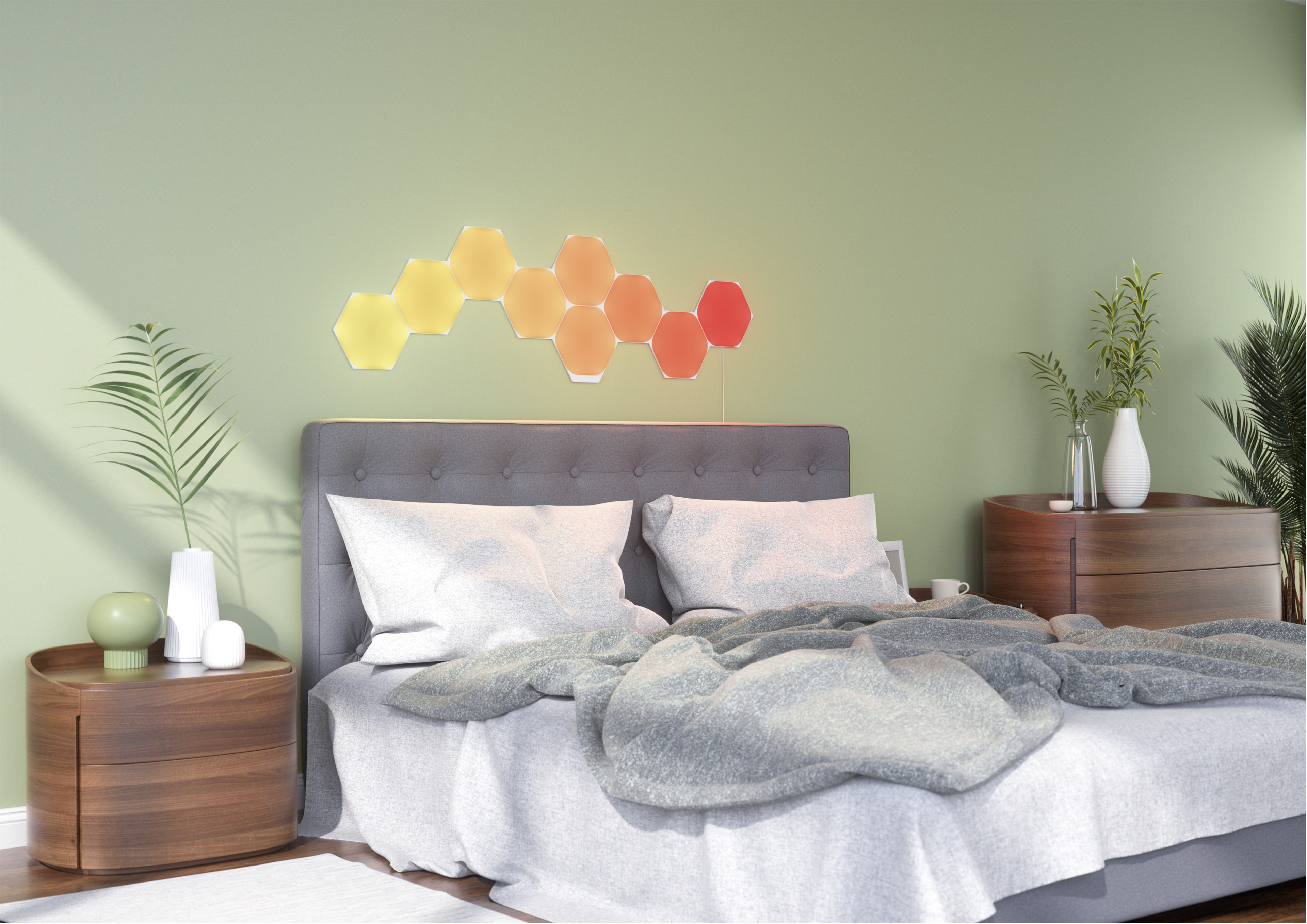 Ein Schlafzimmer mit Bett, Nachttischen und einer Wandleuchte in Form von farbigen Sechsecken.