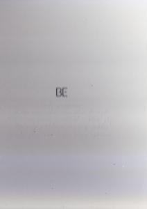 Een grijs oppervlak met de letters 'BE' in het midden. Het oppervlak heeft kleine puntjes.