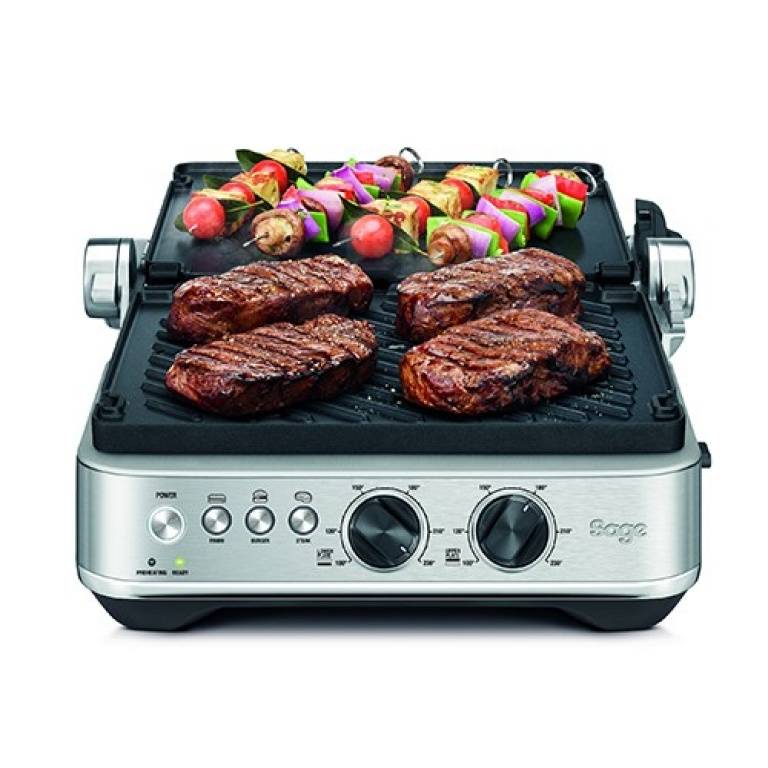 Grill sült steakekkel és zöldségnyársakkal. Gombok és vezérlők elöl.