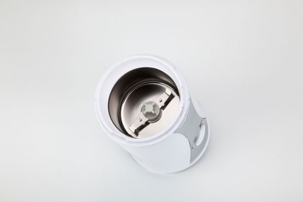 Molinillo de café blanco con cuchillas visibles. Interior con cuenco metálico.