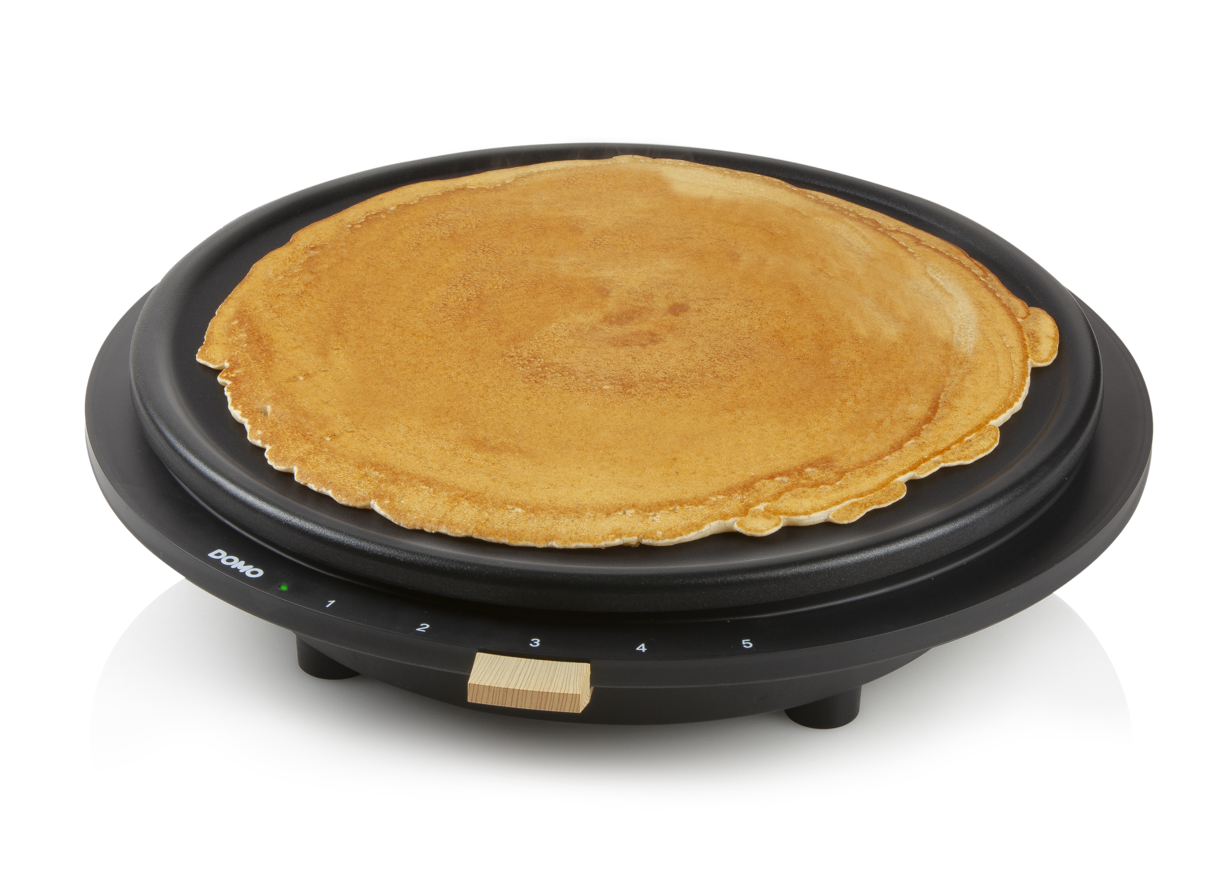Black pancake maker with a pancake on top and a wooden handle.