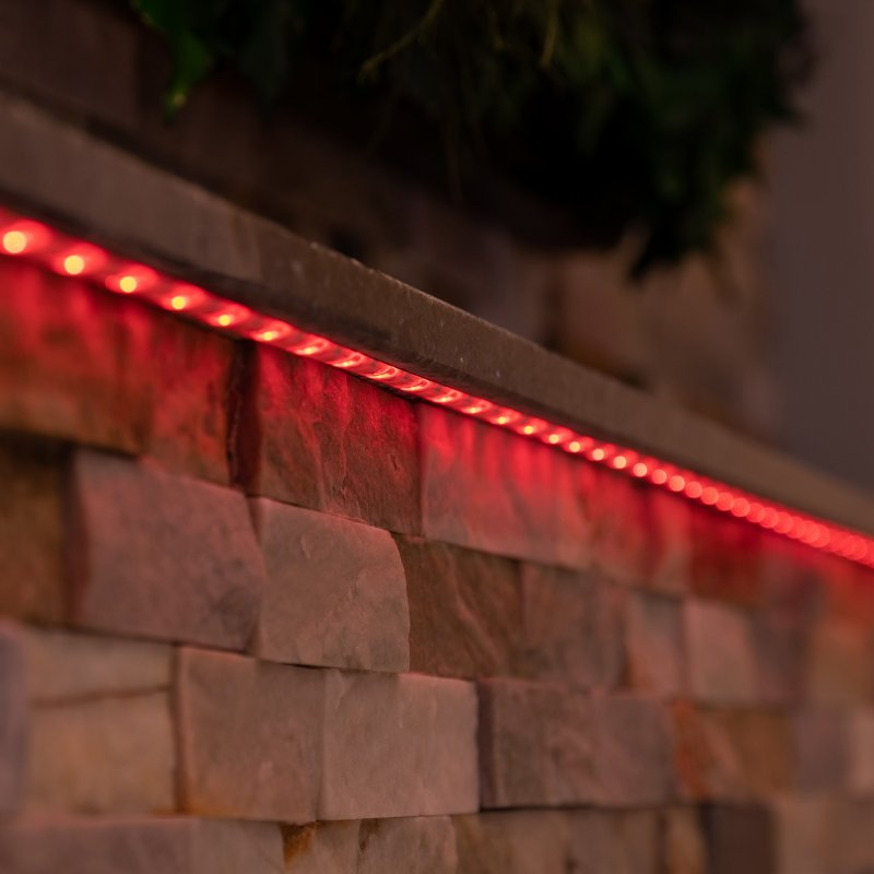 Una striscia luminosa a LED rossa è montata su un muro di pietra.