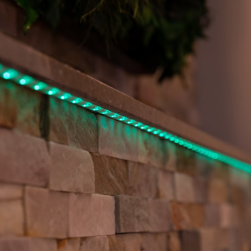 Strisce luminose a LED verdi installate lungo un muro di pietra.