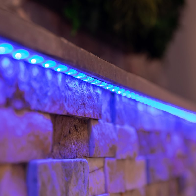 Un muro di pietra con luci LED blu installate lungo il bordo superiore.