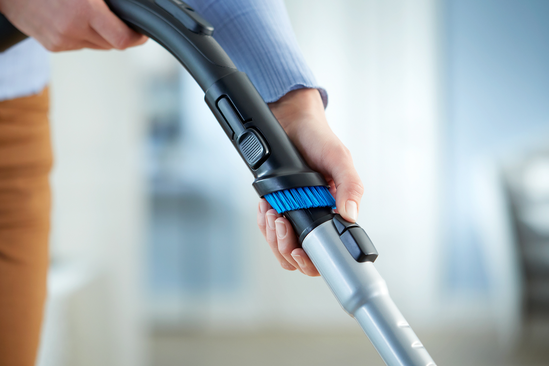 Hand holding the handle of a vacuum cleaner, cleaning the surface.