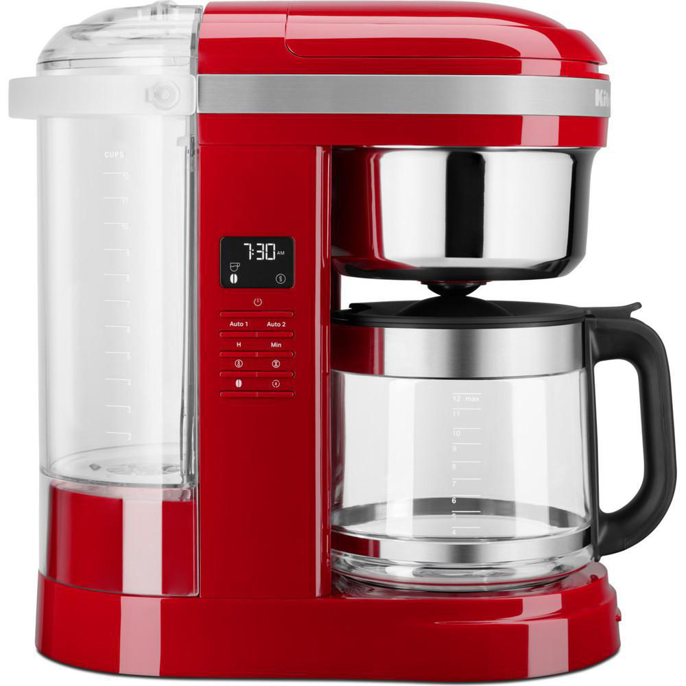 Ein roter Kaffeeautomat mit Glaskaraffe. Eine Digitalanzeige zeigt die Uhrzeit. Das Gerät steht auf einem roten Sockel.