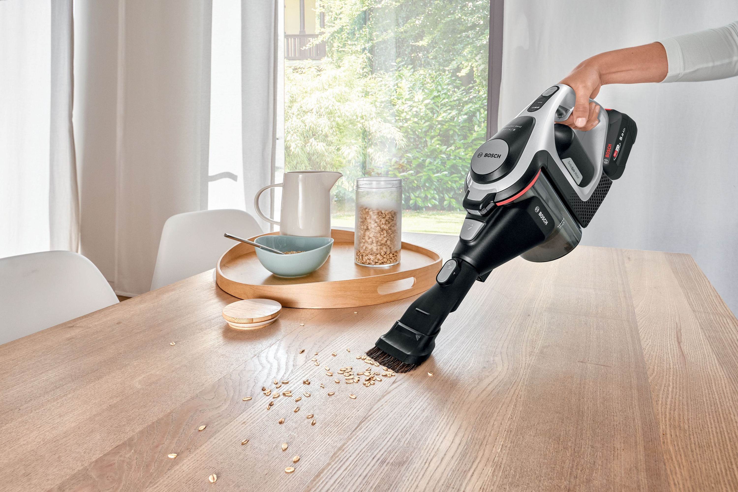 Eine Hand, die Krümel von einem Holztisch absaugt.