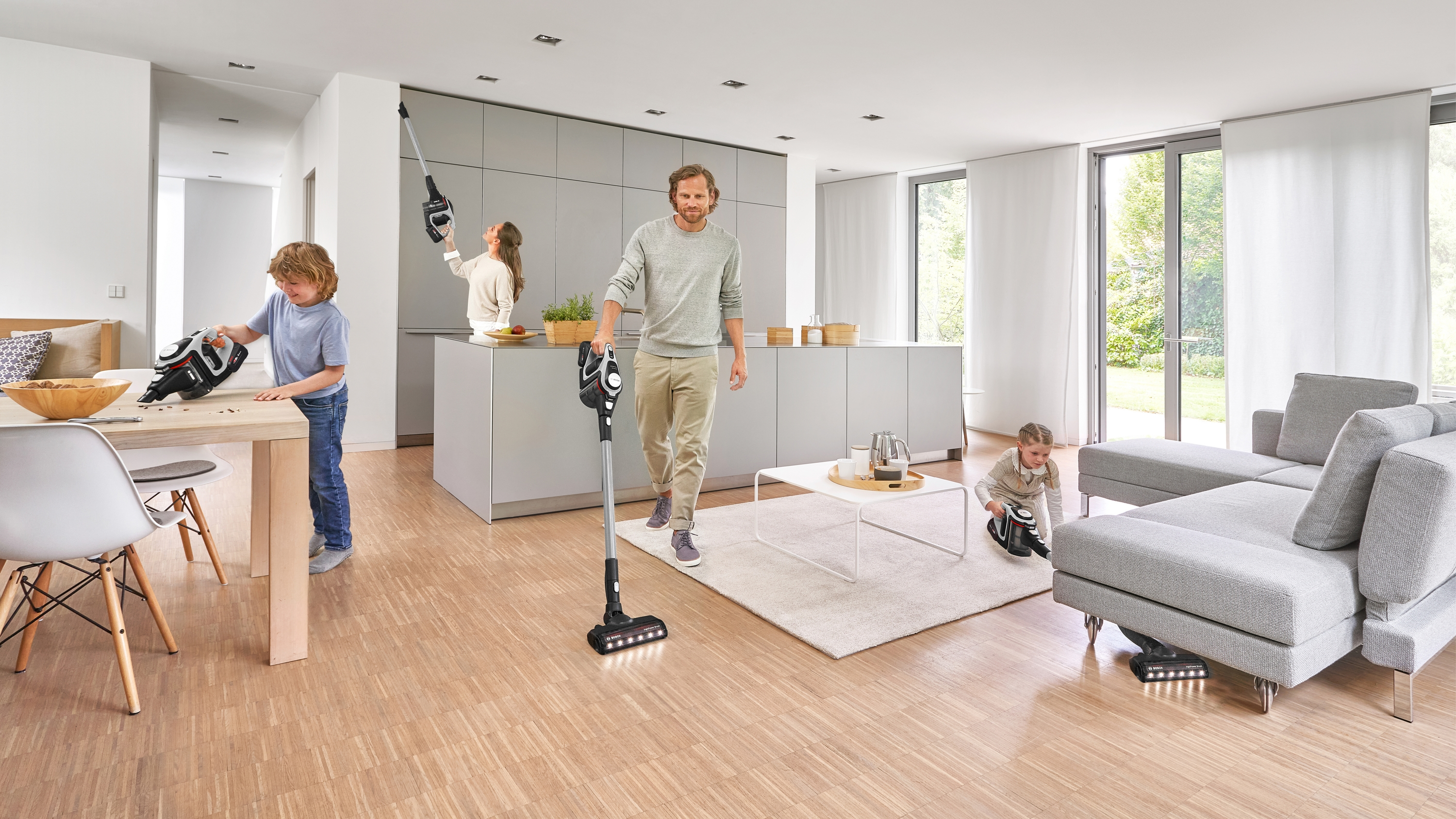 Familie saugt ein Haus. Ein Junge und ein Mädchen saugen, ein Mann geht mit einem Staubsauger.