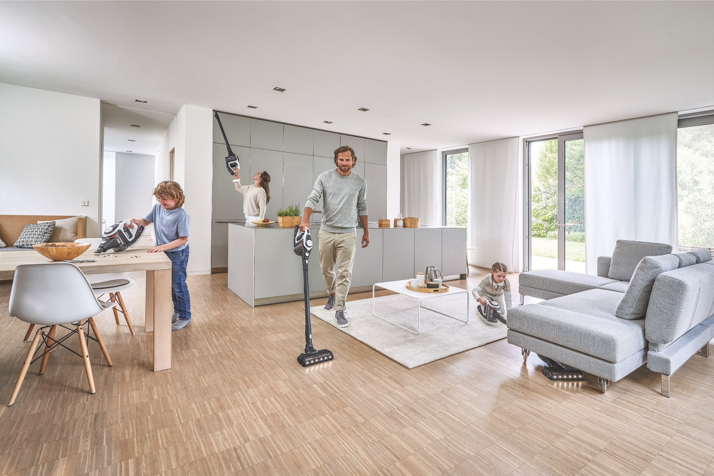 Familie saugt ein modernes, helles Wohnzimmer ab.