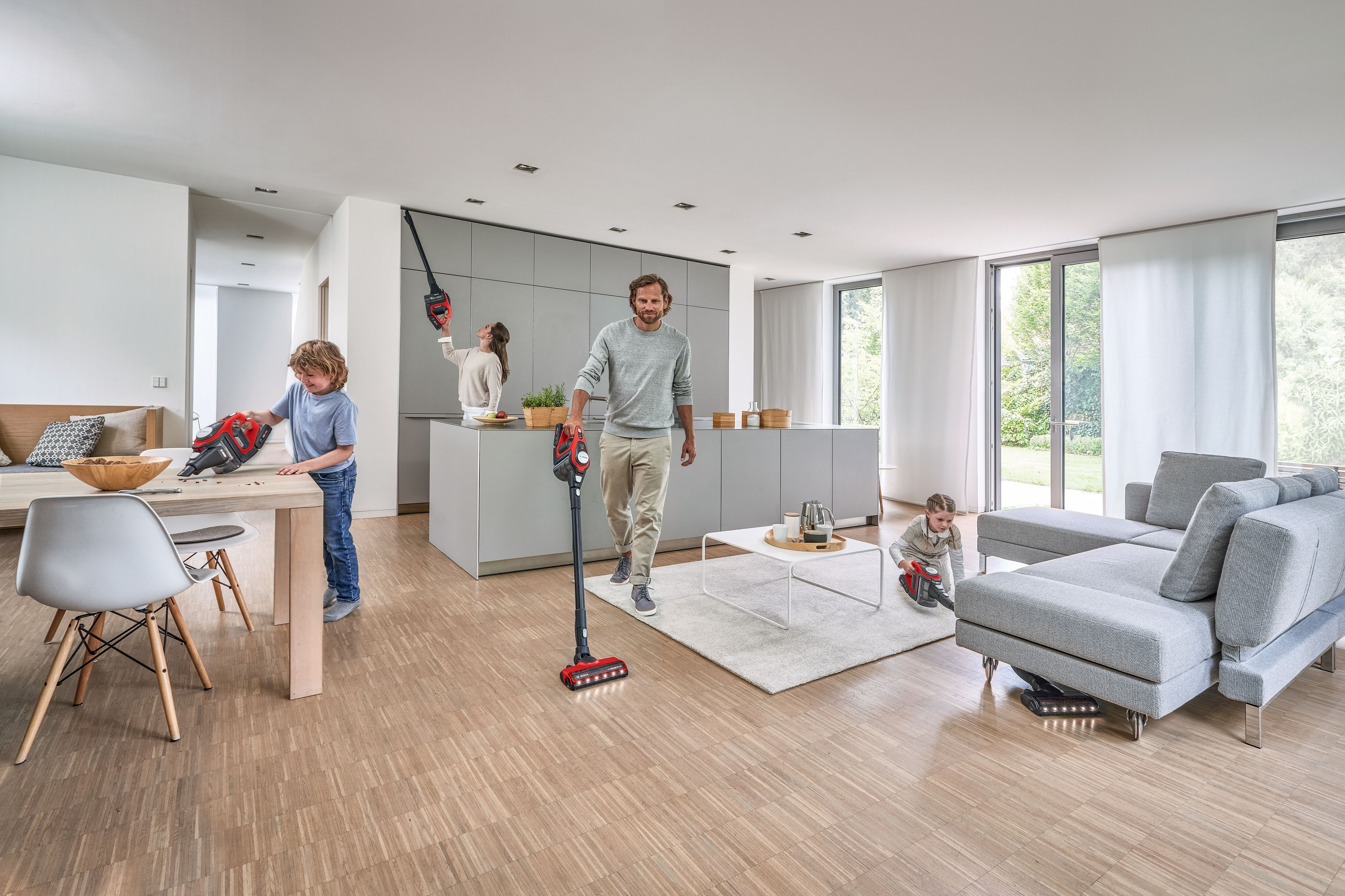 Eine Familie in einem Haus, die Staubsauger benutzt, mit weißem Boden und Möbeln.