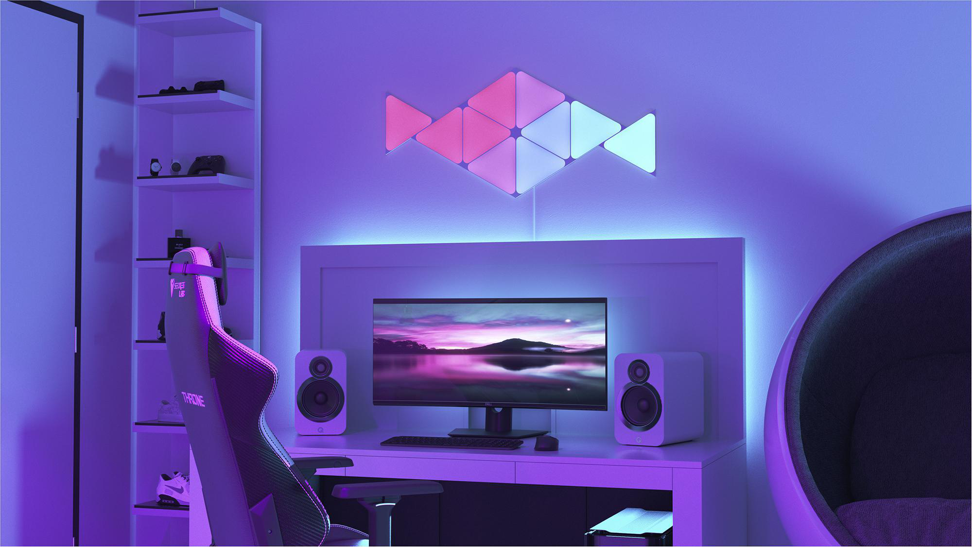 Ein Gaming-Setup in einem Raum mit einem Wand-Lichtdesign. Ein Computermonitor und Lautsprecher stehen auf einem Schreibtisch.