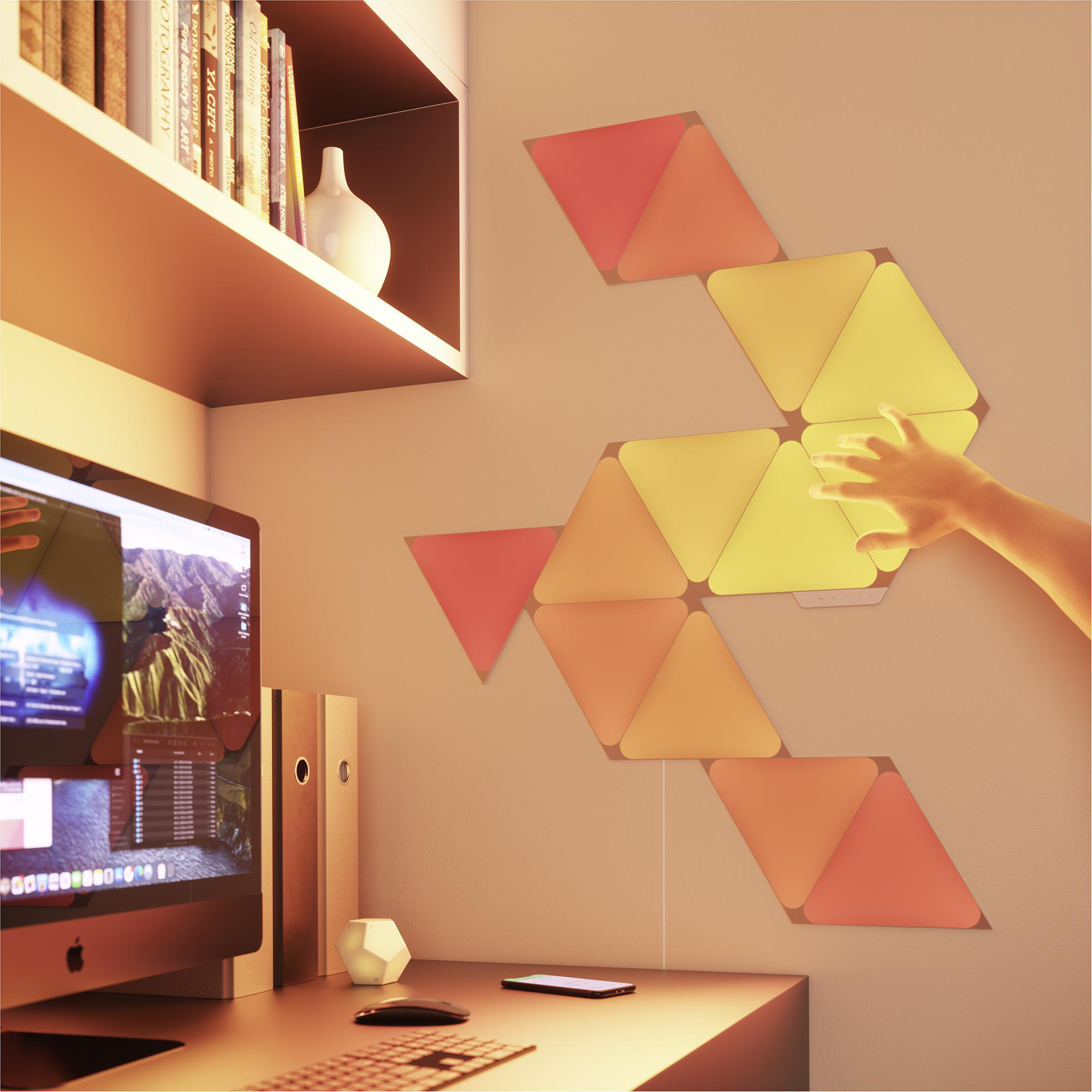 Eine moderne Schreibtisch-Einrichtung mit smarten Lichtern an der Wand, einem Computer und einer Hand.