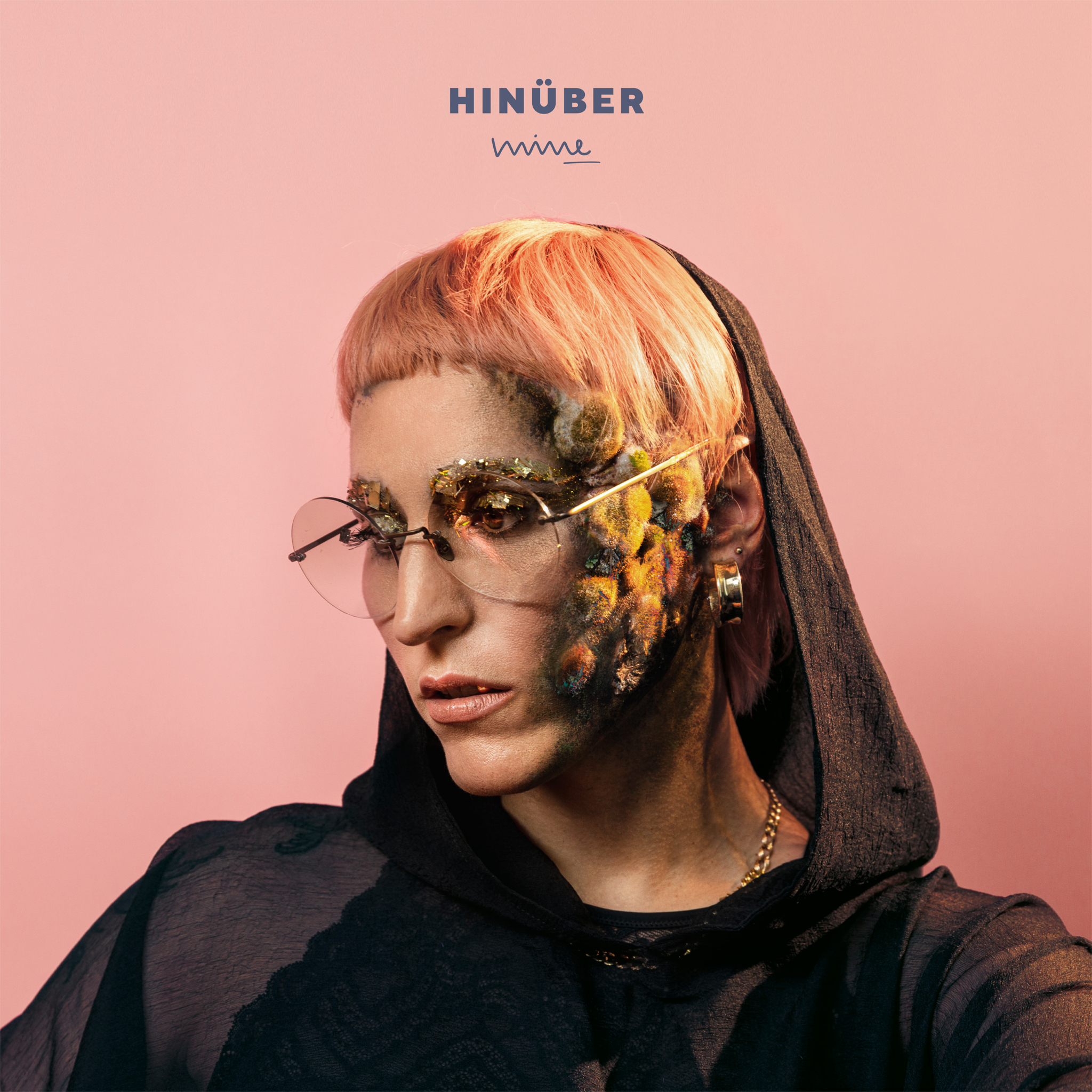 Eine Person mit rosa Haaren und Gesichtsbemalung blickt nach unten. Der Hintergrund ist rosa.