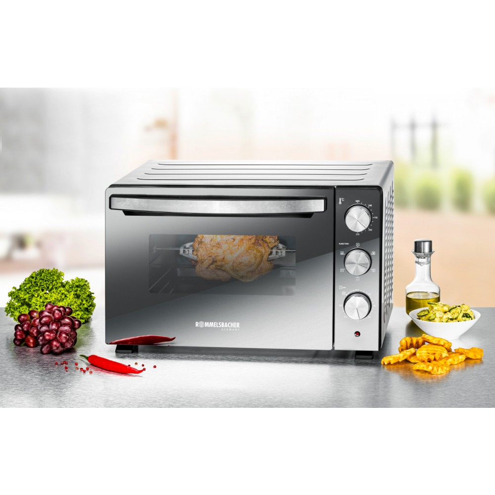 Ein Backofen mit einem Huhn im Inneren und Gemüse in der Nähe. Es hat Knöpfe und eine Glastür auf einer Oberfläche.